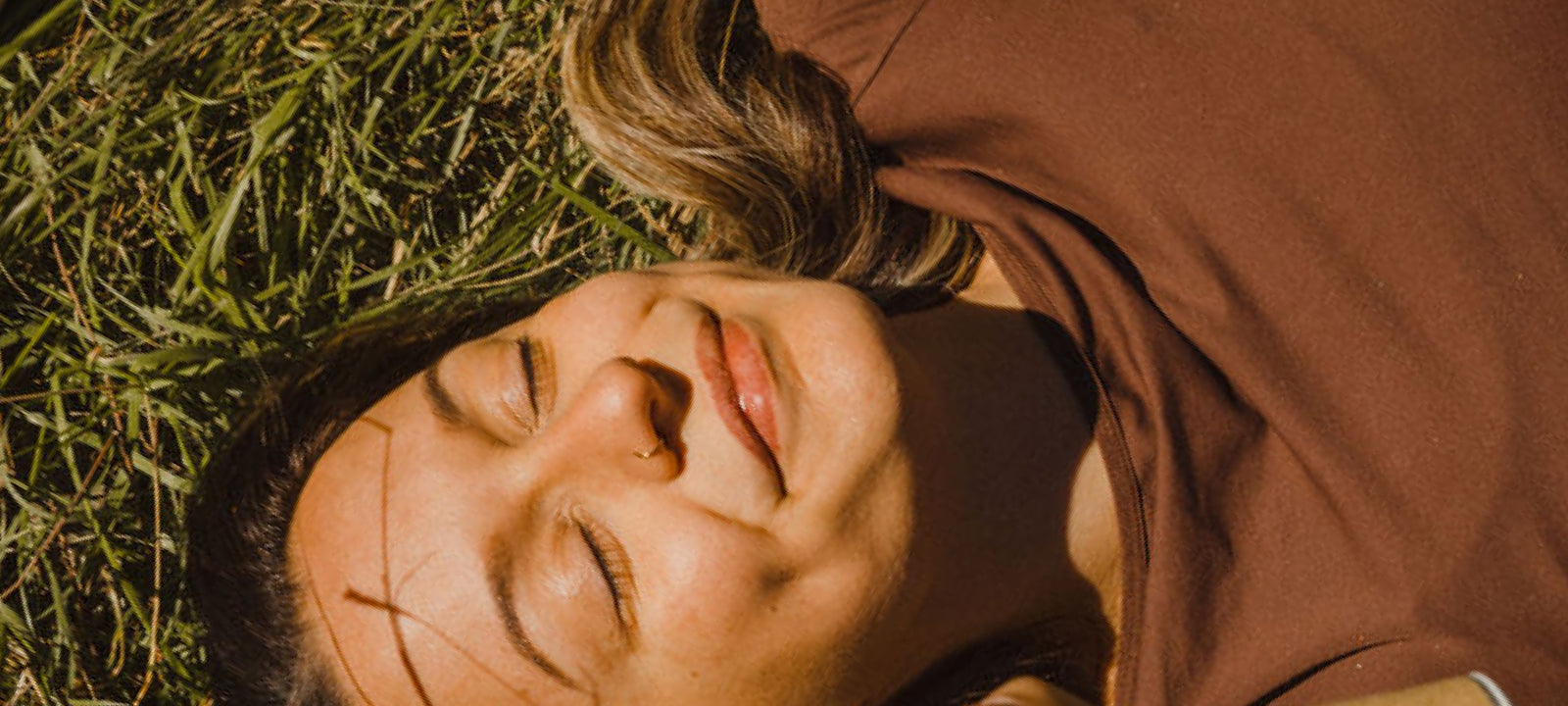 A woman laying down on a field on a sunny day